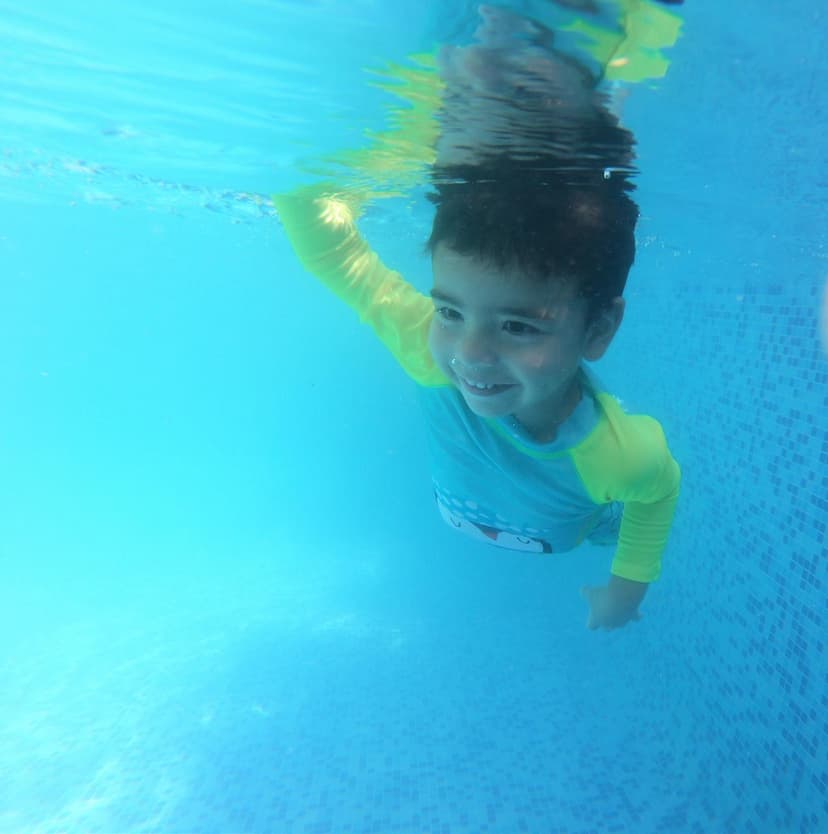 Imagen de un niño nadando en una piscina sonriendo