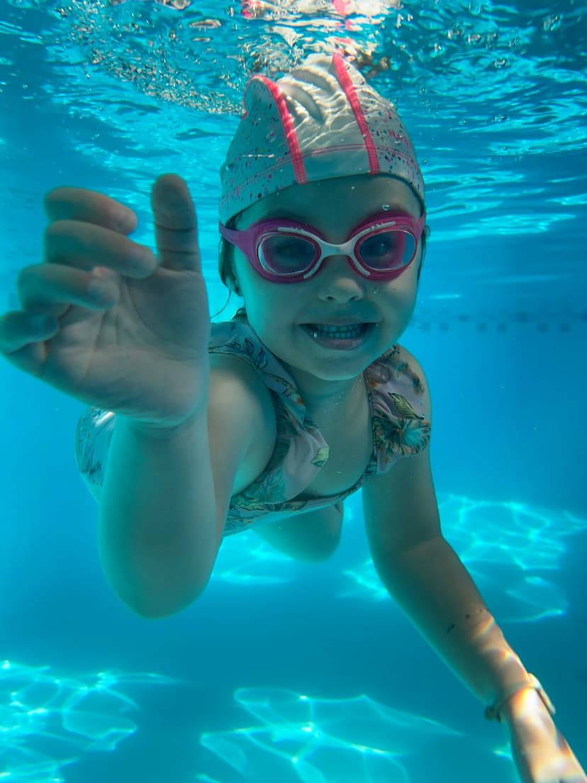 Imagen de un niña feliz nadando en una piscina sonriendo